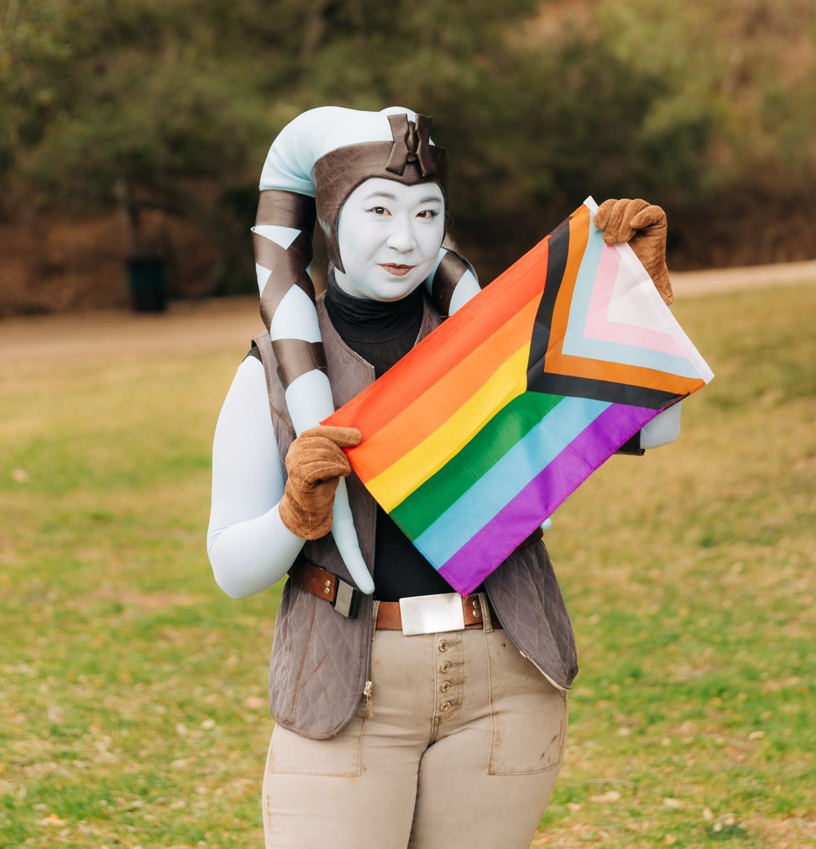 Lorie in her Mission Vao cosplay holding a pride flag.