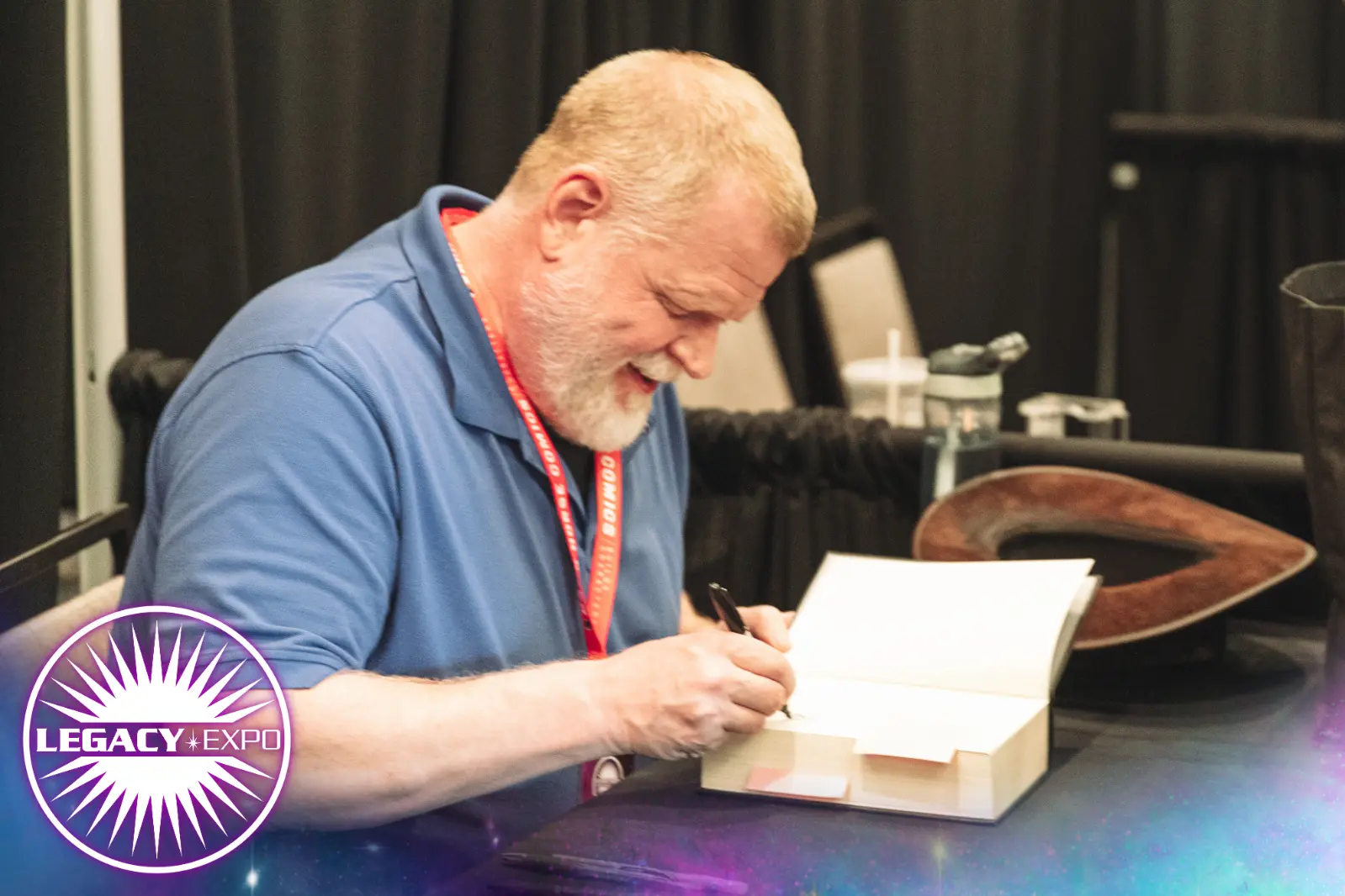 Author Matthew Stover smiles as he signs a book for a fan.